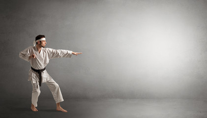 Small karate man fighting in an empty grey copy space