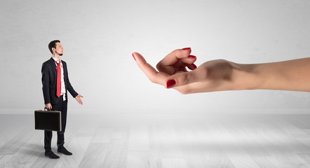 Businessman with kisses on his face in an empty space where a big hand baiting him
