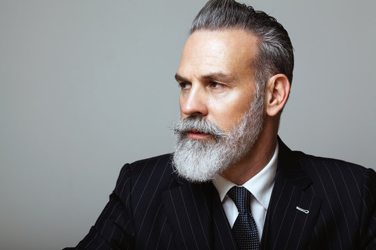 Close-up portrait of bearded gentleman wearing trendy suit over empty gray background. Copy Paste space.
