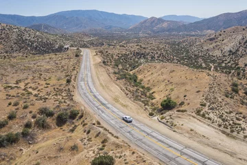 Gordijnen Single car on empty wilderness road in the Mojave Desert of southern California. © kenkistler1
