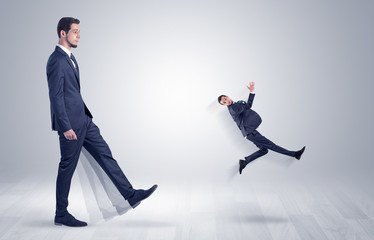 Big man in suit kicking out little himself with simple white wallpaper
