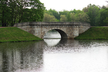 Fototapeta premium a strong summer downpour on the lake. drops of rain fall into the water. Gatchina Park. Historical bridge between two lakes.