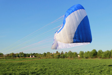 pilot newcomer paraglider is trained on the ground to lift up and hold the blue-white paraplane.