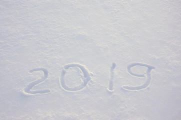 Handwritten digits 2019 in a fresh crisp snow illuminated by the light of rising sun.New year concept.