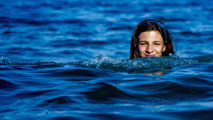 Vacations at sea. Portrait of young beautiful young woman swimming in the transparent sea. (Holiday, rest, travel, childhood concept)