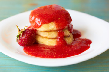 Appetizing pancakes with strawberry syrup.