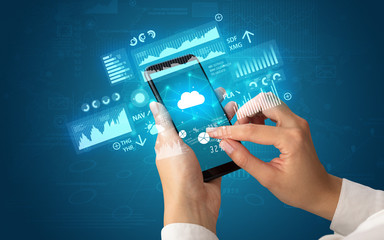 Female hand using smartphone with financial tracking concept illustrated by graphs and symbols