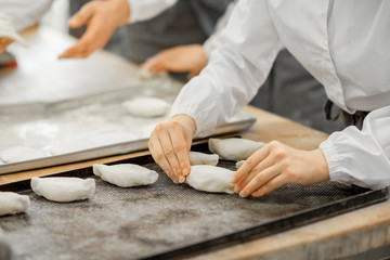 Worker forming raw buns with filling for baking at the manufacturing