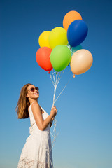 Happy beautiful woman holding balloons in the air