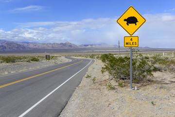 Desert Tortoise crossing warning road sign with mountain backdrop