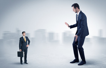 Giant businessman being afraid of small serious executor with suitcase

