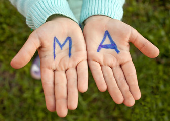 The letters M and A are written in blue on children's palms