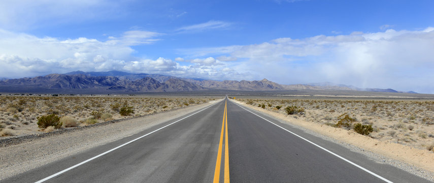 Driving on the open road in the desert with mountain backdrop