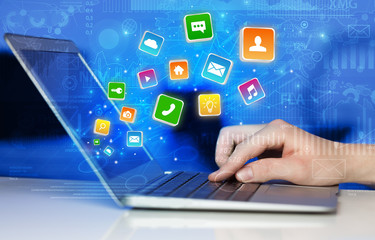 Hand using laptop with bouncing colorful application and global reports and graphs concept
