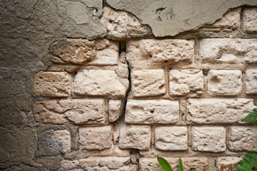 The old wall of white brick with a broken, cracked plaster. Abstract background.