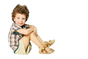 Cute little boy sitting isolated on white background. looking at camera. Copy the space
