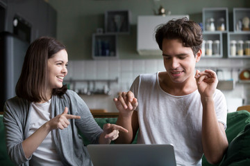 Millennial couple having fun listening to music online on computer application, smiling teenagers...
