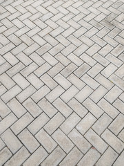 Floor texture of rectangular cement blocks in zigzag pattern.