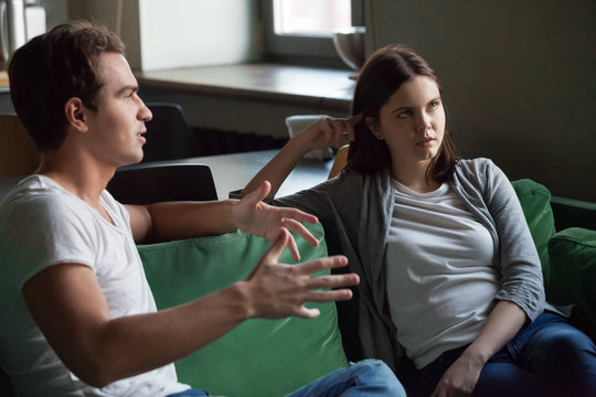 Annoyed Girl Tired Of Listening To Boring Boyfriend Sitting On Sofa At Home, Bored Woman Not Interested In Tedious Monologue Of Talkative Nerd Friend Or Husband Disbelieving Dull Story Concept