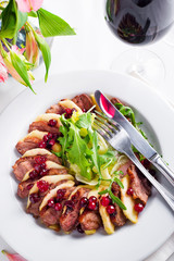 Salad with slices of duck breast with apples and salad under cowberry sauce