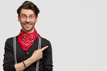 Fashionable male hipster in high spirit, has stubble, wears stylish bandana, has cheerful...