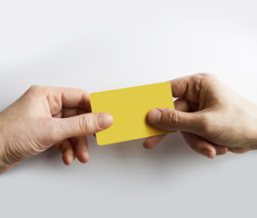 Closeup of male hand giving empty yellow color credit card to waiter.
