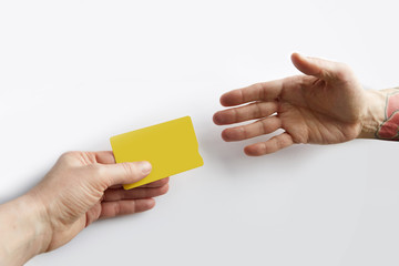 Closeup of male hand giving empty yellow color credit card to waiter.