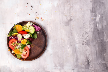 Healthy salad with fresh vegetables and souse in wooden plate