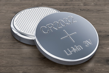 Two button cells on the wooden table, 3D rendering