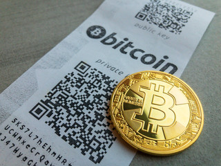 Golden bitcoin coin lying on the paper receipt