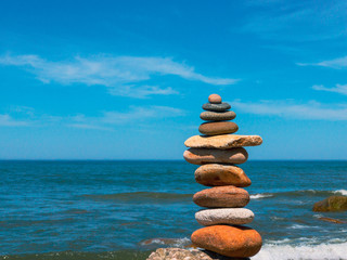 Fototapeta na wymiar Stones in the pyramid stand on the sandy sea beach
