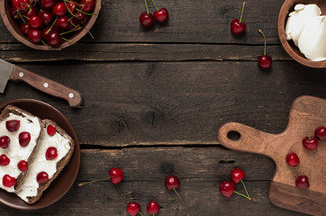 Wooden background with cherry berries, sandviches and plates full of cherry another variation