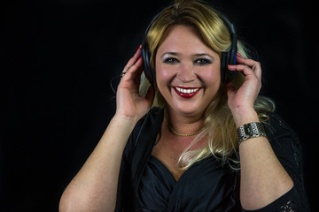 Gutgelaunte blonde Frau hört Musik über Kopfhörer