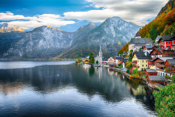 Scenic view of famous Hallstatt mountain village with Hallstatter lake See in beautiful golden morning light in fall