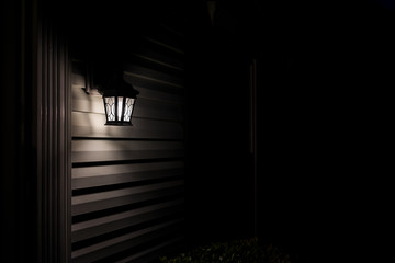 Dark night evening with house exterior lamp lantern, illuminated front door porch with black...
