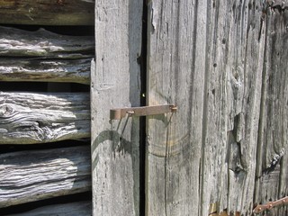 rusty latch on old weathered wood door on smoke house