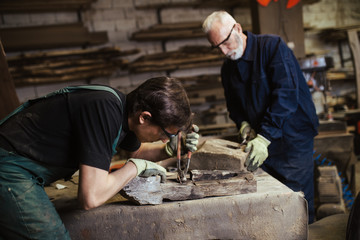 Two master carpenters working together in their woodwork or workshop.
