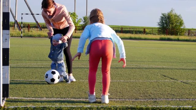 A happy mother with children playing soccer on a football field, score a goal, play in the air, lifestyle, the concept of the family.