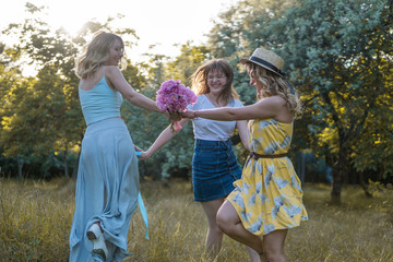 Fototapeta premium Group of girls friends making picnic outdoor. They dance roundelay with each other. bachelorette, party