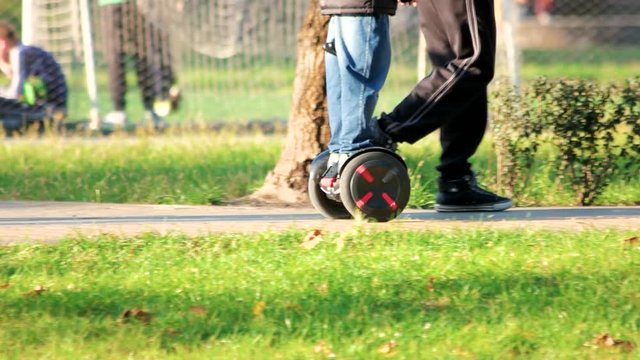 Boy riding gyroscooter in the park. Walking strolling people. Autumn park.