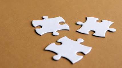 Fototapeta premium Puzzle three pieces&nbsp;on&nbsp;the&nbsp;brown&nbsp;background.