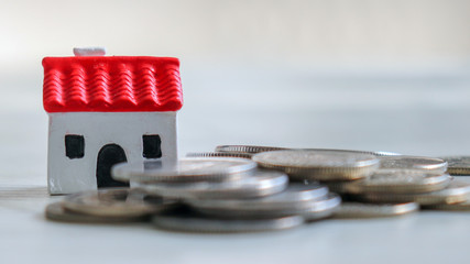 A miniature house and pile of coins.