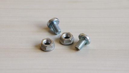 Two bolt and two nut on the wood background. Bolt and nut of different shape.