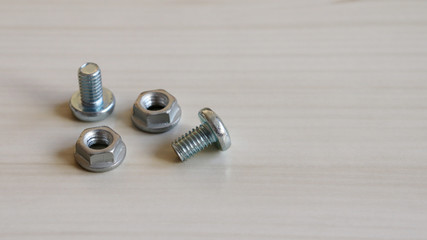 Two bolt and two nut on the wood background. Because bolts and nuts are different shapes,...