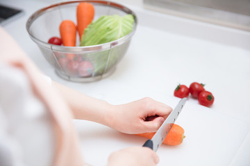 キッチンのまな板の上でニンジンを切る女の子