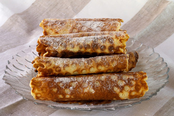 Homemade pastries in the form of rolls of thin dough, folded up by a slide on a glass plate.