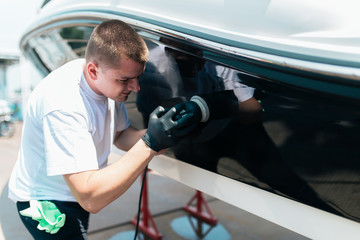 Boat maintenance - Man with orbital polisher polishing boat in marina. Selective focus.