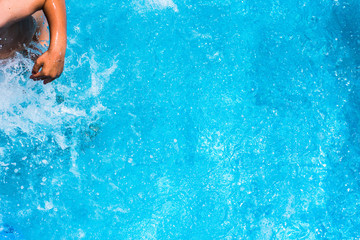 Child splashing in the cool water of a pool in summer