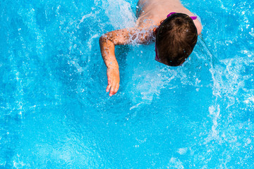 Child splashing in the cool water of a pool in summer