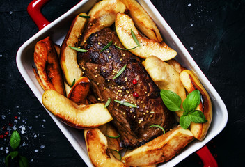 Pork tenderloin baked with quince on a baking sheet, gray background, top view